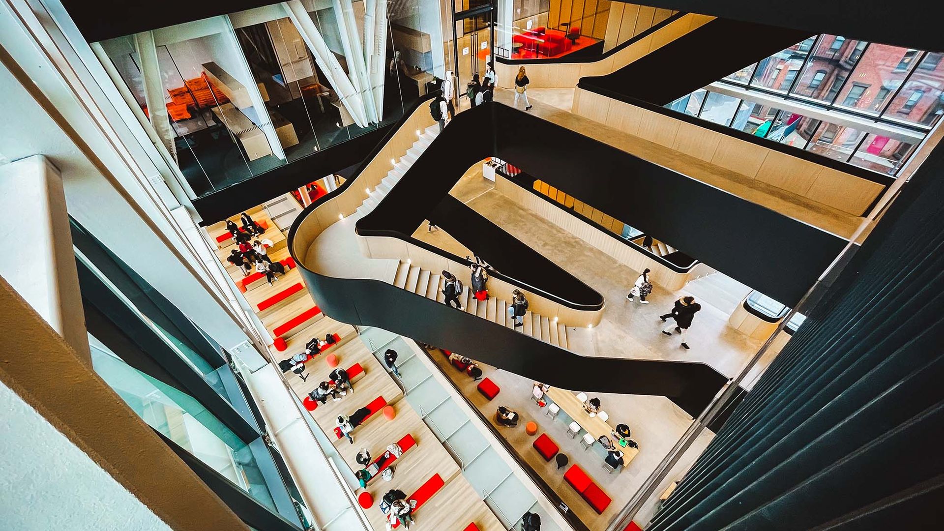 Photo: Overhead shot of students walking and gathering in and around a large set of black and wood butterfly stairs.