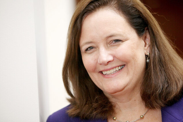 Photo: Kate Walsh, CEO of Boston Medical Center, Leaving to Lead State’s Health and Human Services Department. Headshot photo of a white woman with short brown hair and wearing a purple blazer and thing gold necklace smiles for the camera.