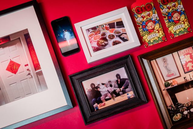Photo: Flatlay of various picture frames and mementos showing various Lunar New Year memories. Pictures show a traditional memorial, a group of friends goofing off, a white door with a red symbol on it, a phone showing a photo of fireworks, a tabled filled with dishes of Asian food, and red envelopes with cartoon artwork on the front.