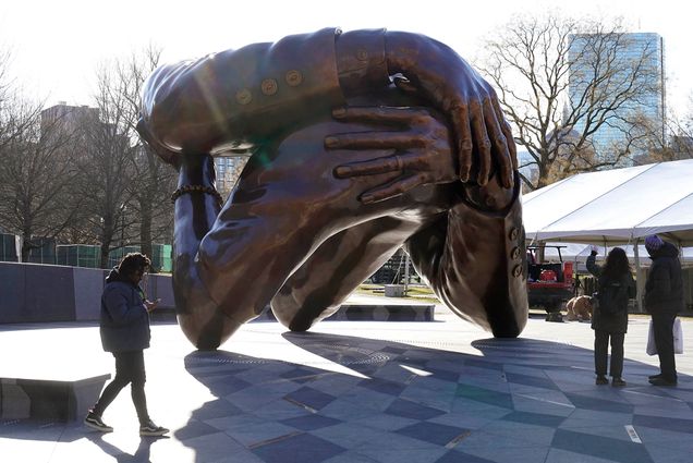 A man reaches to touch a detail of the 22-foot-high bronze sculpture, The Embrace, a memorial to Martin Luther King, Jr. and his wife, Coretta Scott King, in the Boston Common, January 10. The sculpture, consisting of four intertwined arms, was inspired by a photo of the Kings embracing when MLK learned he had won the Nobel Peace Prize in 1964. The statue is to be unveiled during ceremonies Friday, January 13. (AP Photo/Steven Senne)