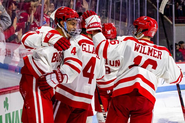 BU Men's Hockey Team in red and white jerseys on the ice with full equipment. The Terriers defend their 2022 Beanpot Championship Monday against Northeastern in a rematch of the 69th Beanpot final. [Credit: Kyle Prudhomme]