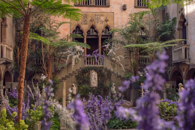 Photo: A photo of the courtyard in the Isabella Stewart Gardner Museum. There are lavender plants in the foreground and the second level in the background. The time of day is dusky.