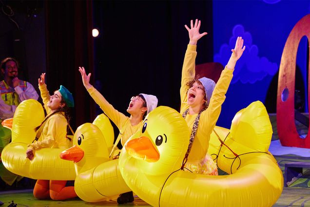 Bonnie Shao [playing Quack] and Echo Kaufman [Playing Mack] throw their hands in the air in the duck costumes they wear for Make Way For Ducklings, a musical at the Wheelock Family Theatre.