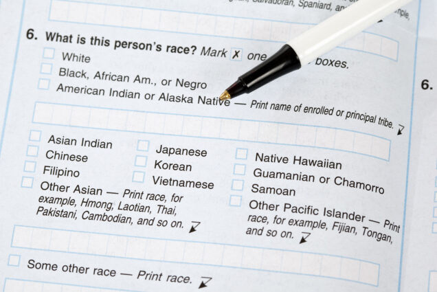 Photo: Closeup of a US Census form. Question that can be seen asks "What is this person's race?" and lists various checkbox options as well as boxes to write in answers. A black and white pen lays on top of the document.