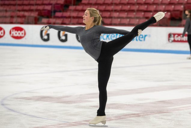Photo: A member of the BU Figure Skating Club wearing black leggings and a grey shirt does a trick on skates at Agganis Arena