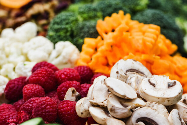 Photo: A zoomed photo of various different vegetables such as mushrooms, carrots, cauliflower, and a handful of raspberries on the lefthand side.