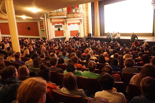 Photo: A large audience of people in what appears to be a movie theatre