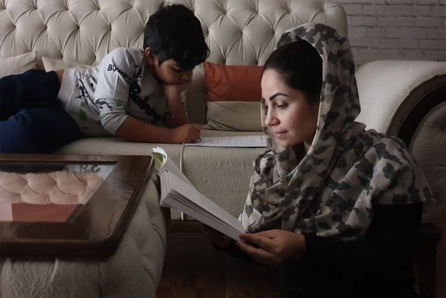 Photo: A woman and her son read books. The woman is wearing a headscarf. Women’s rights advocate Homeira Qaderi, pictured here with her son, Siawash, faced death for her activism when the Taliban retook Afghanistan in 2021.