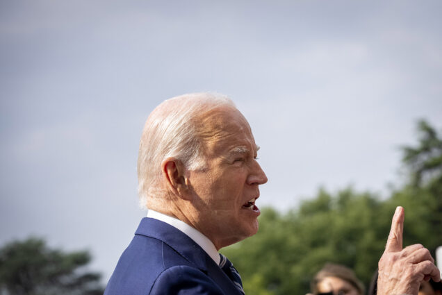 Photo: President Joe Biden, an older white man with white hair and wearing a white collared shirt and blue blazer, is shown from the side. The sleep mark of a CPAP machine can be seen on his cheek.