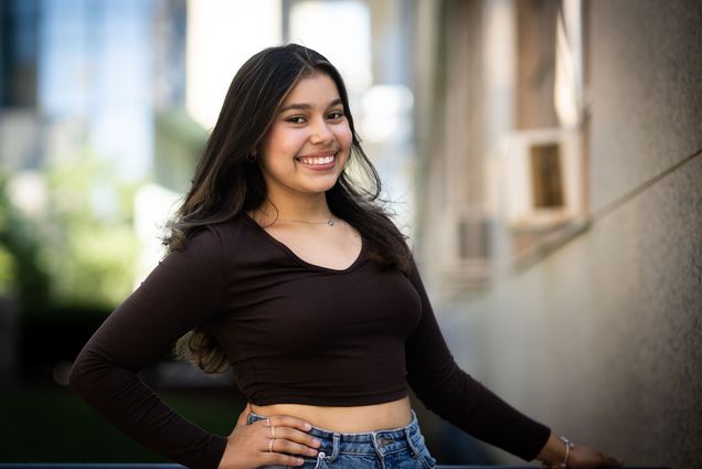 Photo: A young college student with long black hair and a smile poses for the camera.