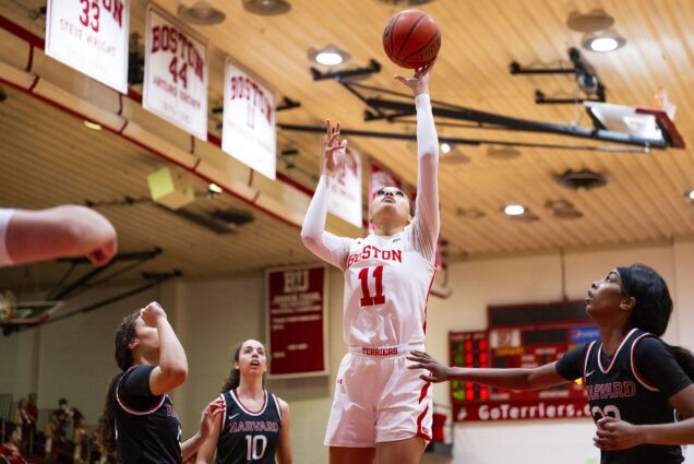Photo: Caitlin Weimar goes to make a basket. She wears her white uniform and is playing in one of BU's gyms.