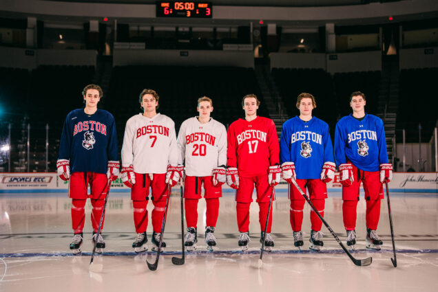 Photo: Three sets of brothers stand in a line and pose for the camera. All have their hockey sticks and are wearing their issued red hockey pants.