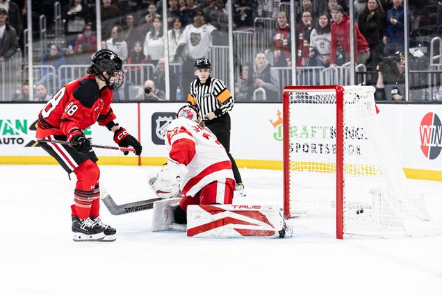 Photo: Winning shot of Skylar Irving in her red and black uniform for Northeastern shooting against BU's goalie in overtime play.