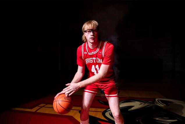 Photo: A college basketball player wearing all red with red hair and goggles dribbling a basketball