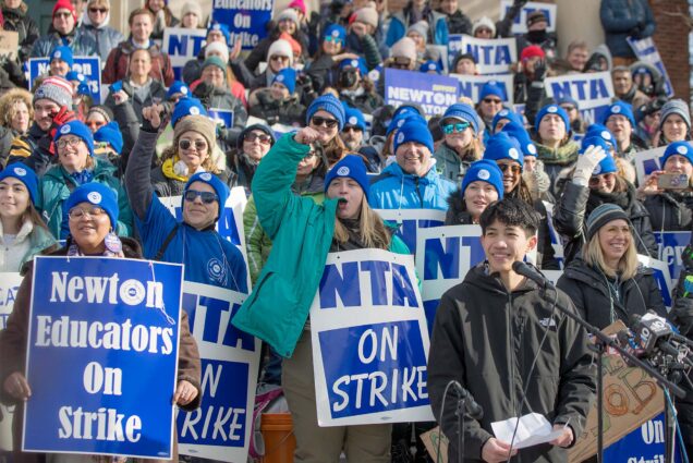 Photo: A large group of teachers on strike in Newton MA, holding blue signs that read "Newton Educators on Strike"
