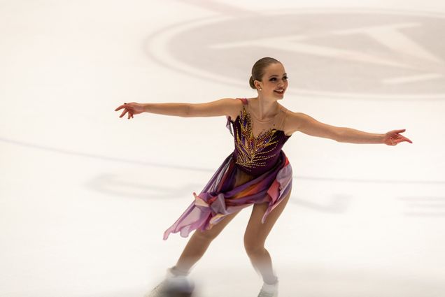 Photo: Clara Neal skates with her arms open and wide as she smiles during her performance.