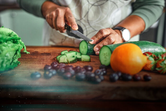 Photo: A stock image of an individual cutting a cucumber with various other rainbow fruits and vegetables on the cutting board. A glitch overlay rest on top of the image.