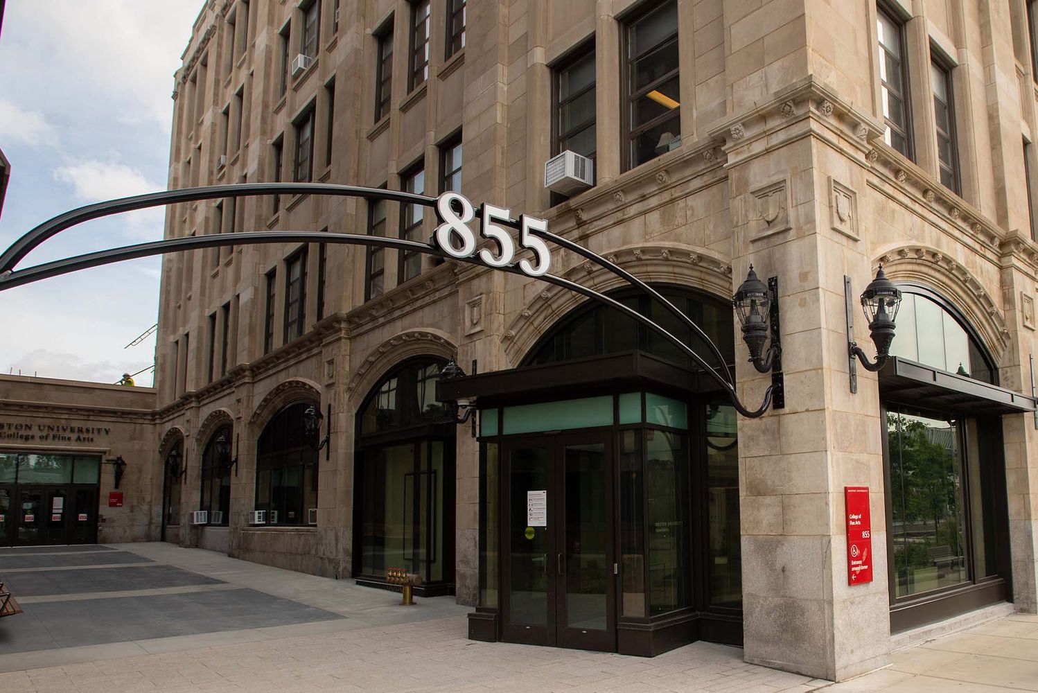 Photo: A large building with tan-colored stone and black doors. There is a black metal arch with the numbers "855" outside of it