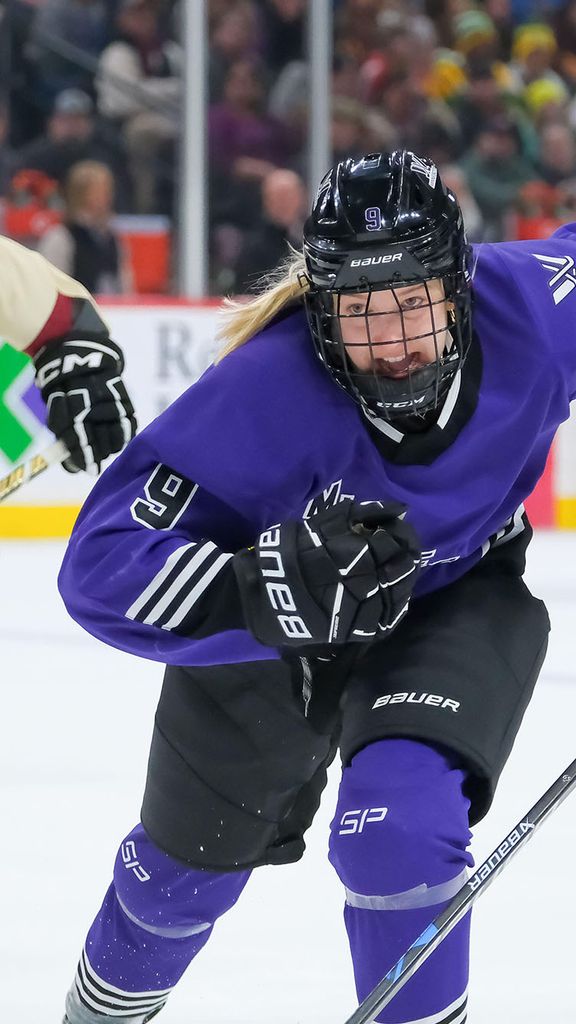 Photo: A Professional Women's hockey player wearing a Minnesota jersey that is purple with white trim, skating towards a puck at a recent game