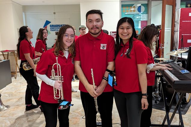 Photo: A group of 3 people standing with band instruments in red Boston University pep band jerseys