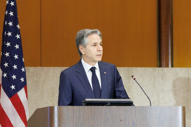 Photo: Secretary of State Antony Blinken wearing a suit standing at a podium