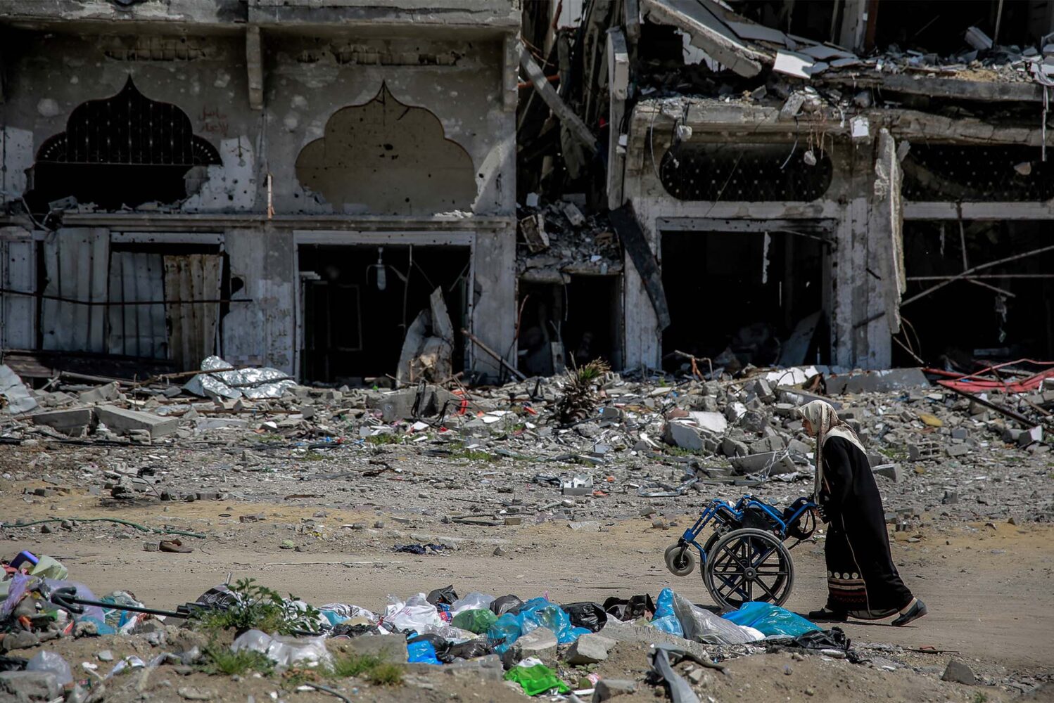 A woman pushing a wheelchair next to destroyed buildings in the northern Gaza Strip on March 21, amid the ongoing violence between Israel and Hamas
