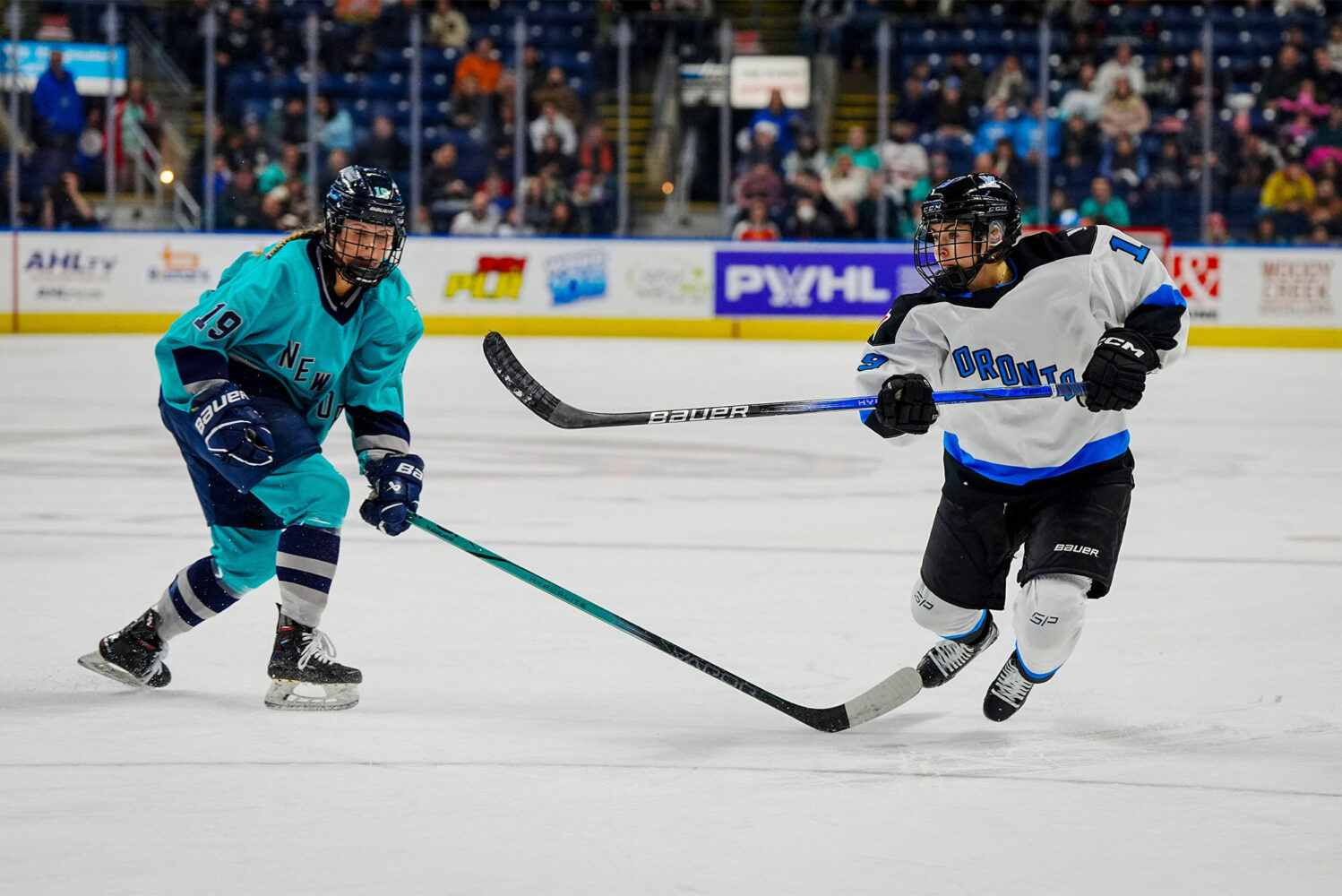 Photo: A Professional Women's hockey player wearing a Bridgeport CT jersey that is white with blue trim, taking a shot on goal at a recent game