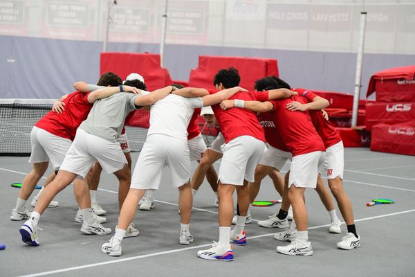 Photo: Members of the BU Mens tennis team put their arms together in a celebratory chant at a recent meet