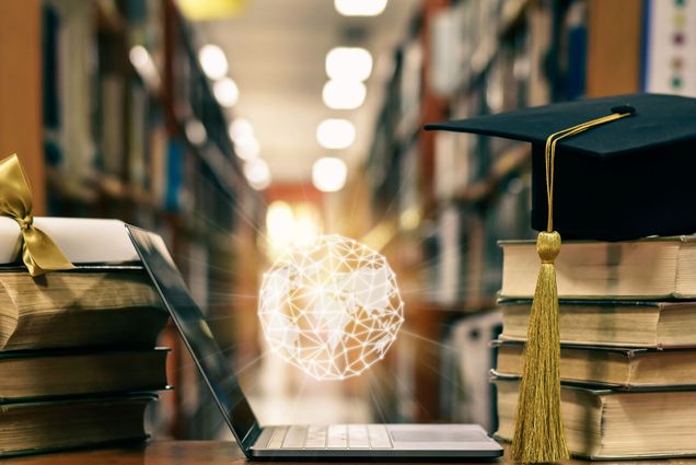 Photo: A picture of an open laptop with a glowing orb hovering above it. To its left there is a diploma wrapped in gold ribbon and to its right there is a graduation cap. Both are on top of stacks of books