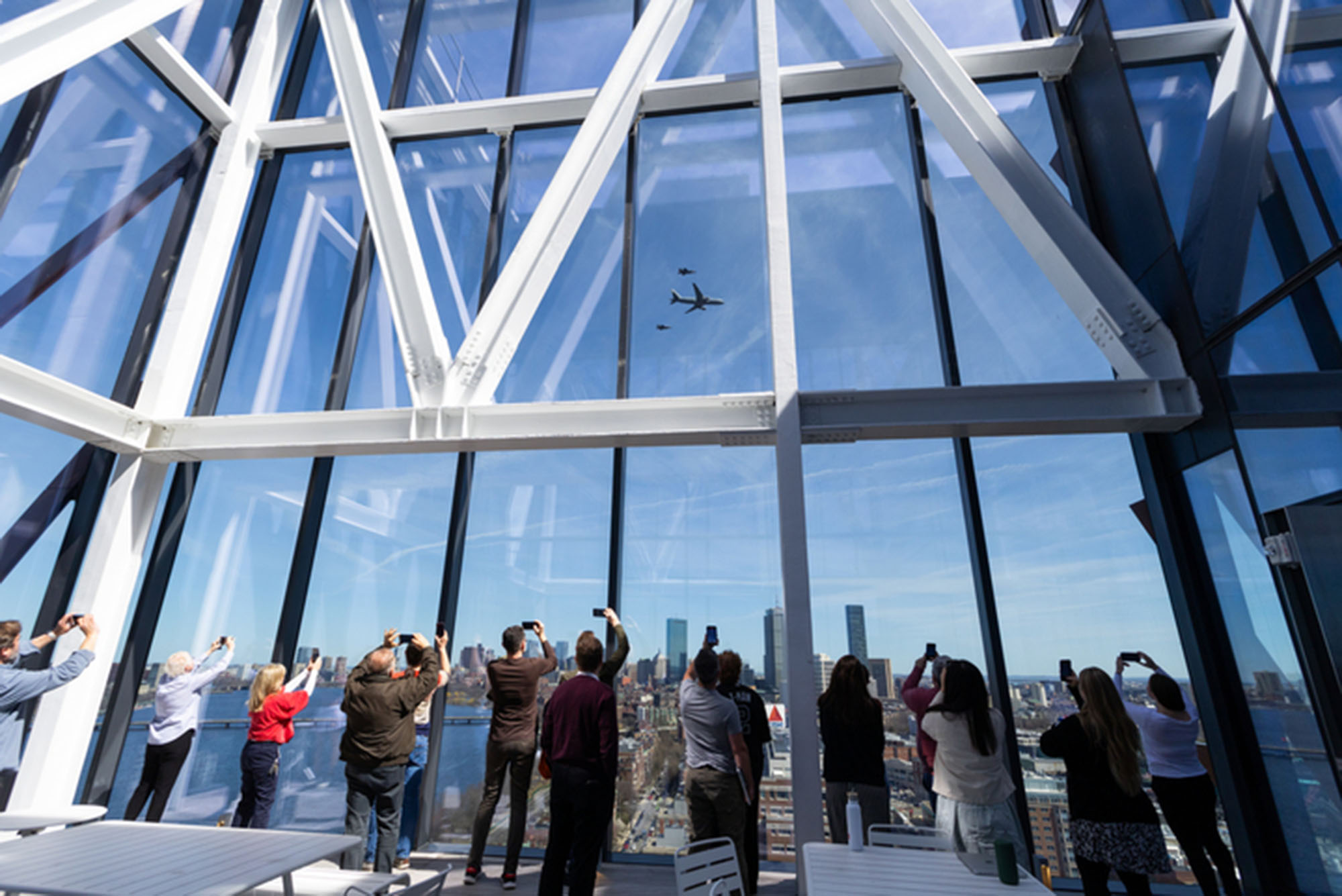 Photo: Many people looking out of a window and taking photos as planes fly by