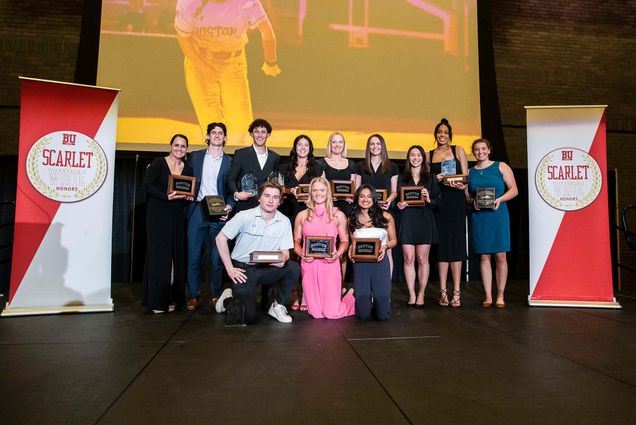 Photo: A picture of many people posing with awards on a stage. There are banners on the stage that read "BU Scarlet White Honors"