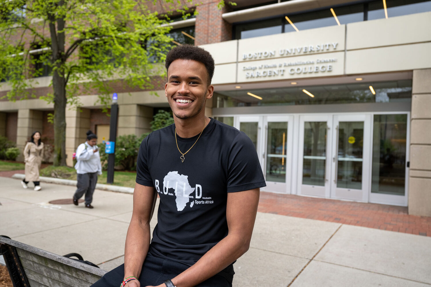 Photo: A picture of a man smiling and posing in front of a Boston University building