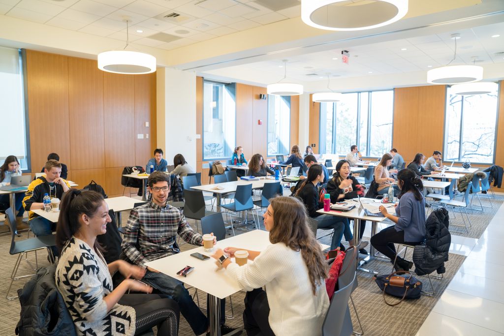 Smatterings of students in an open lecture hall working on group projects