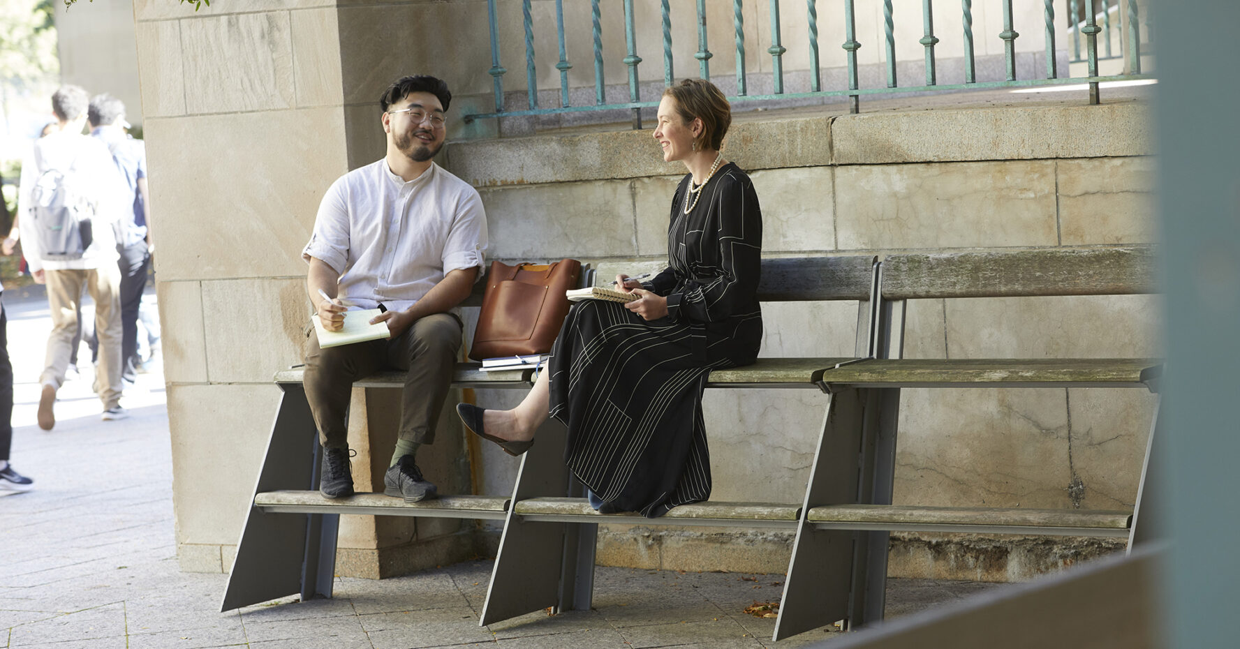 Julie Dahlstrom and James Cho ('22) sit on a bench outside the Law Tower.