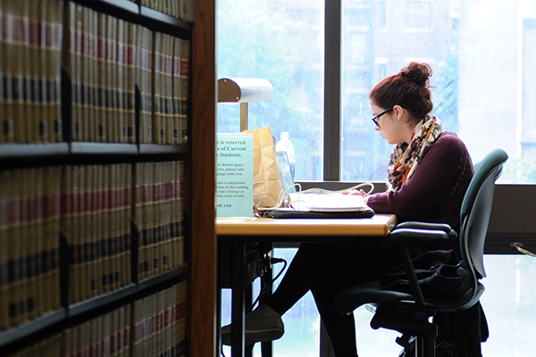 A female student works quietly in the library.