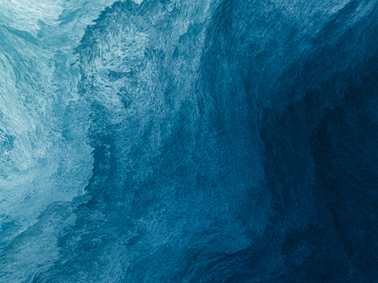 An abstract view of ocean water with varying shades of blue, creating a textured aquatic surface.