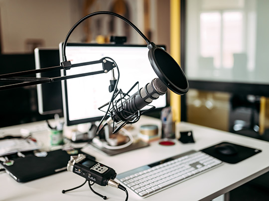 A microphone positioned in front of a computer in a recording studio