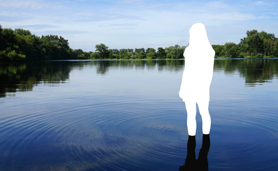 White silhouette of person standing in ankle-deep water with ripples going out across the water