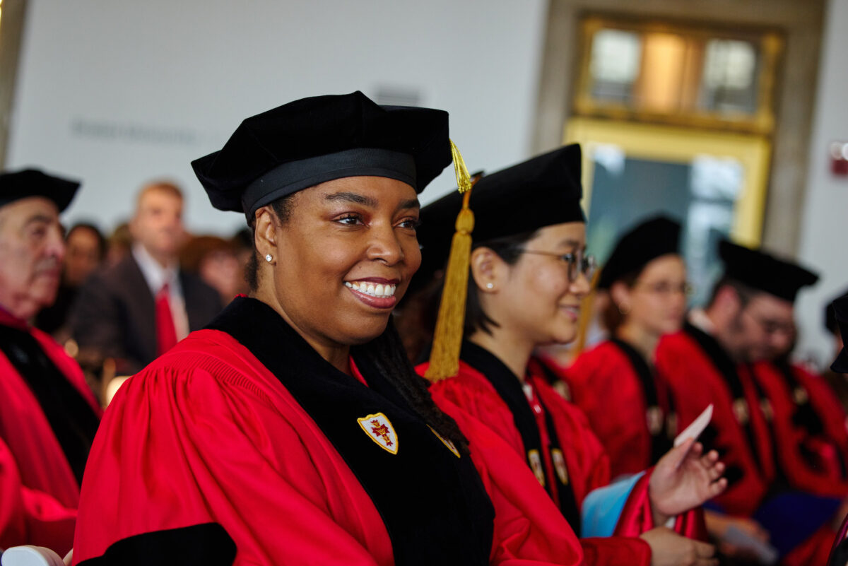 Graduating doctoral candidate smiling as she waits for diploma