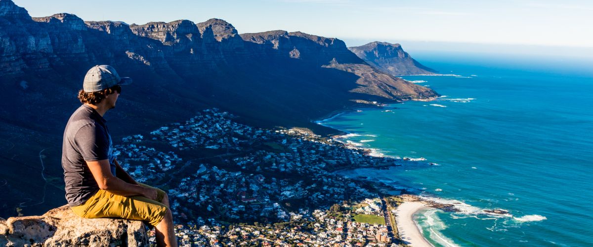 man sitting on a cliff above Cape Town South africa with a view of the city