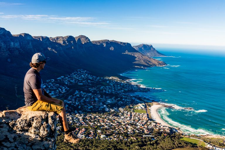 man sitting on a cliff above Cape Town South africa with a view of the city