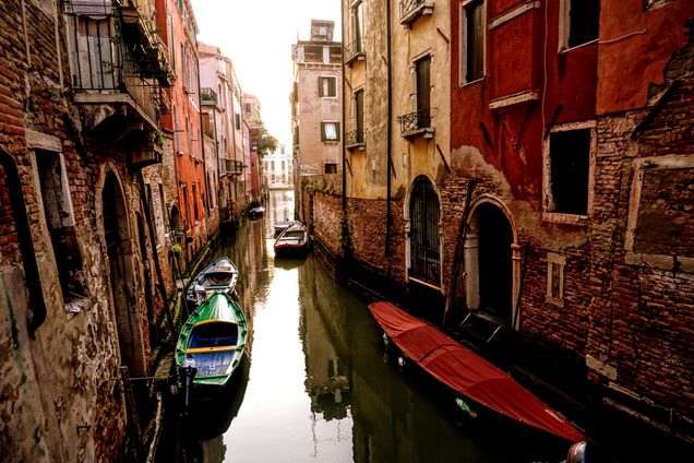 boats tied up against houses in canal in Venice