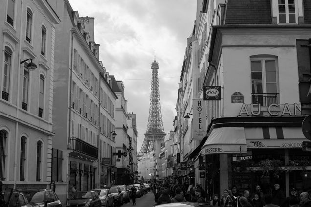 black and white picture of teh eiffle tower from a paris street