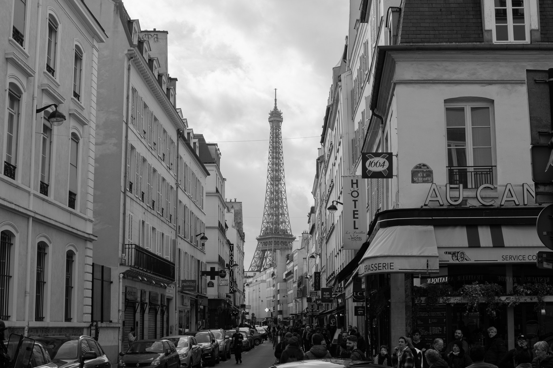 black and white picture of teh eiffle tower from a paris street