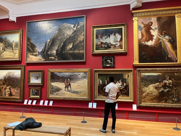MAn looking at painting in a museum gallery