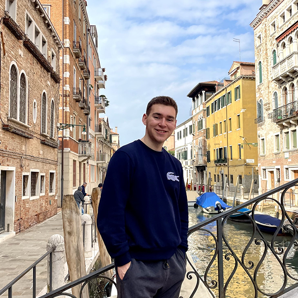 Photo of Matt Lutkins on a bridge in Italy with the water and buildings behind him