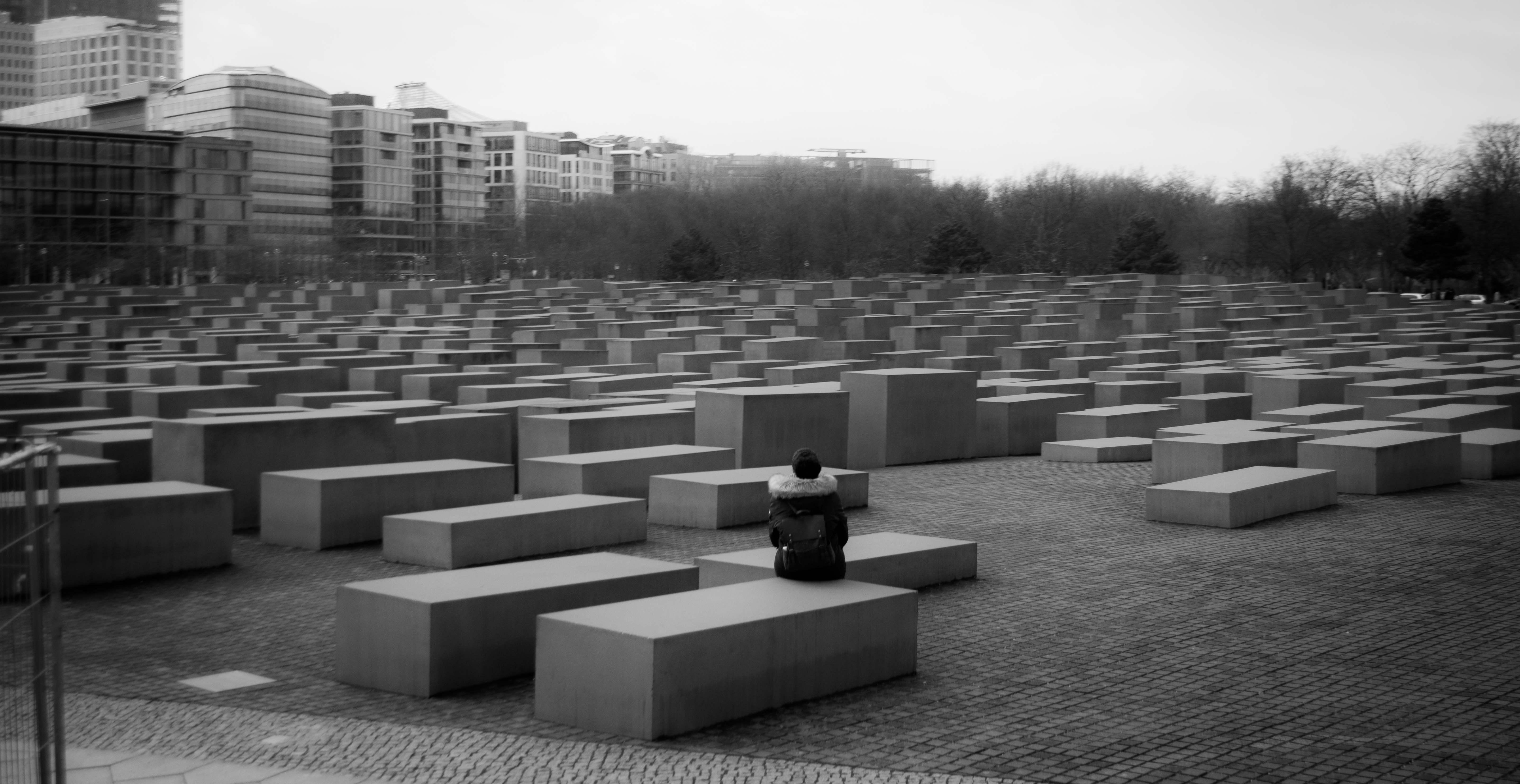 phot of a woman sitting on a block at the holocaust memorial in Berlin