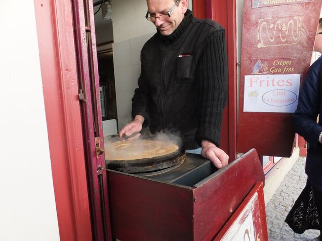 man making a crepe in the doorway of a cafe in Paris
