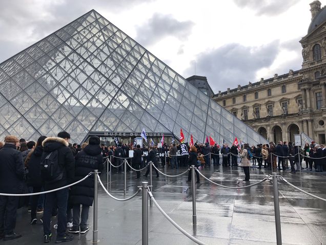 people waiting on line to enter the Pyramid entrance at the Louvre Paris