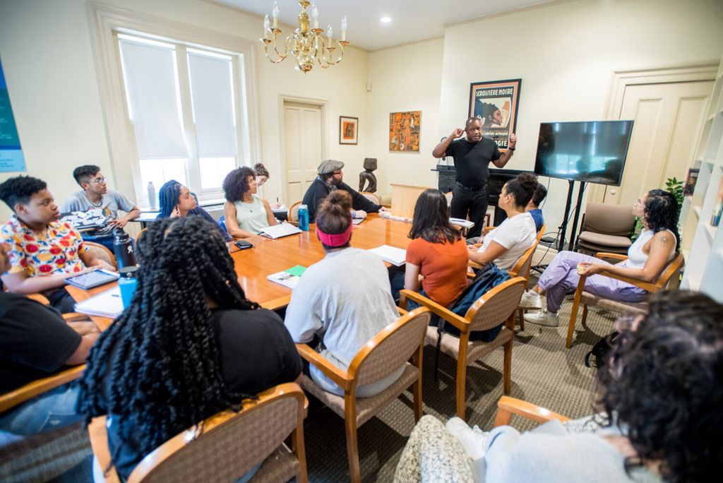Dr. Louis Chude-Sokei lecturing a class of students around a conference table.